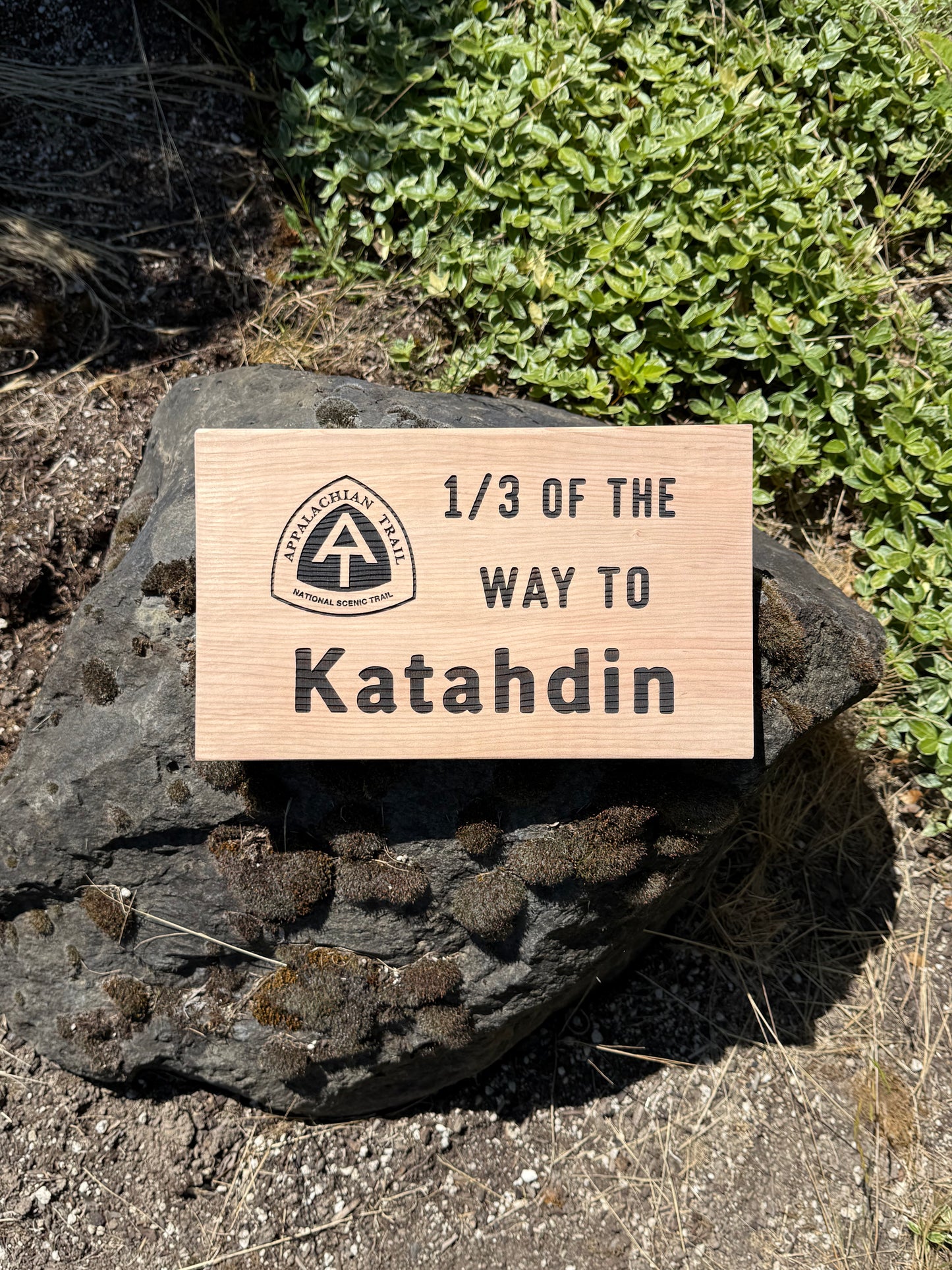Wooden sign on a rock with text '1/3 of the way to Katahdin and a logo.