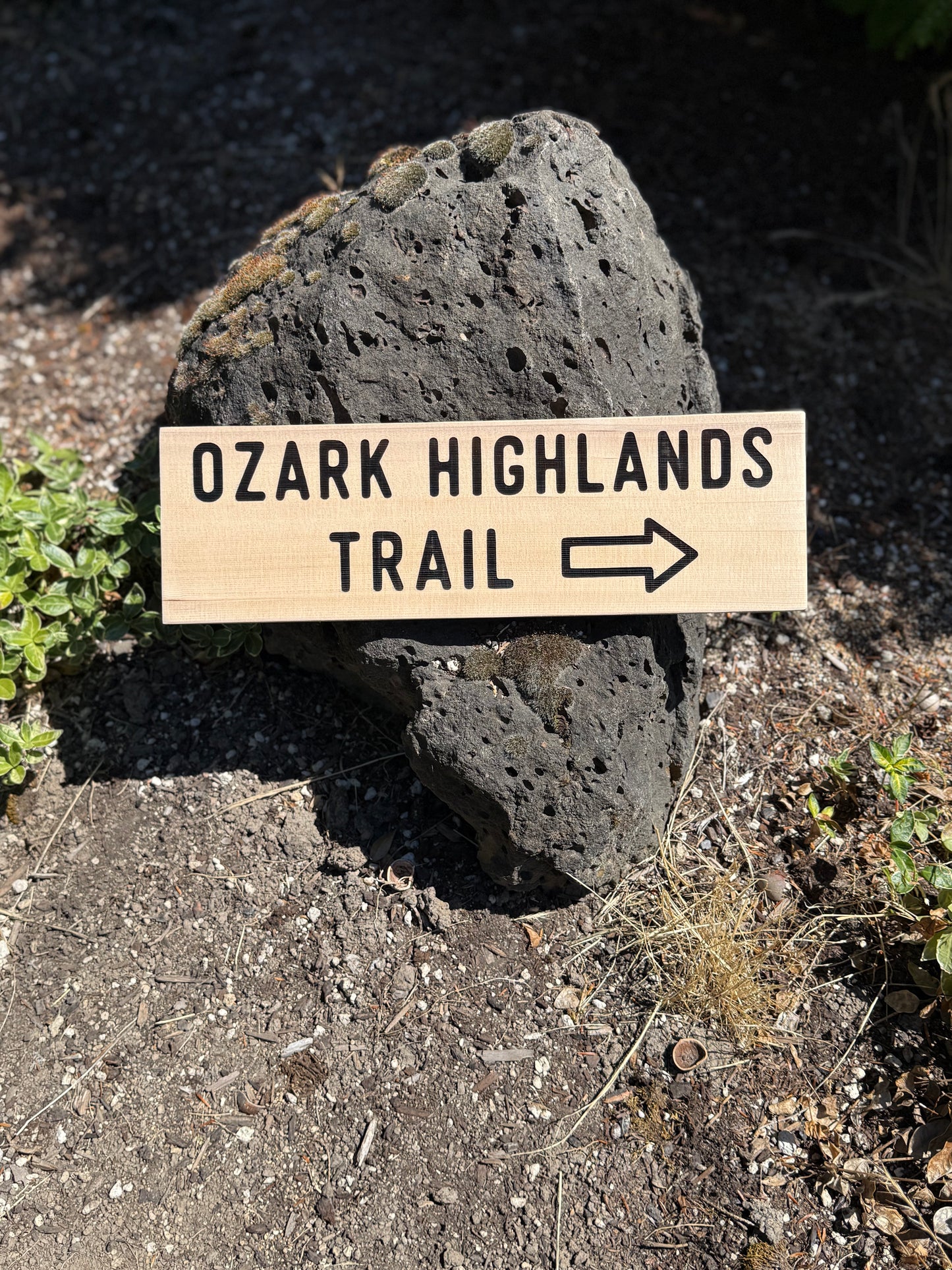 Wooden sign pointing to the Ozark Highlands Trail on a rock in a natural setting.