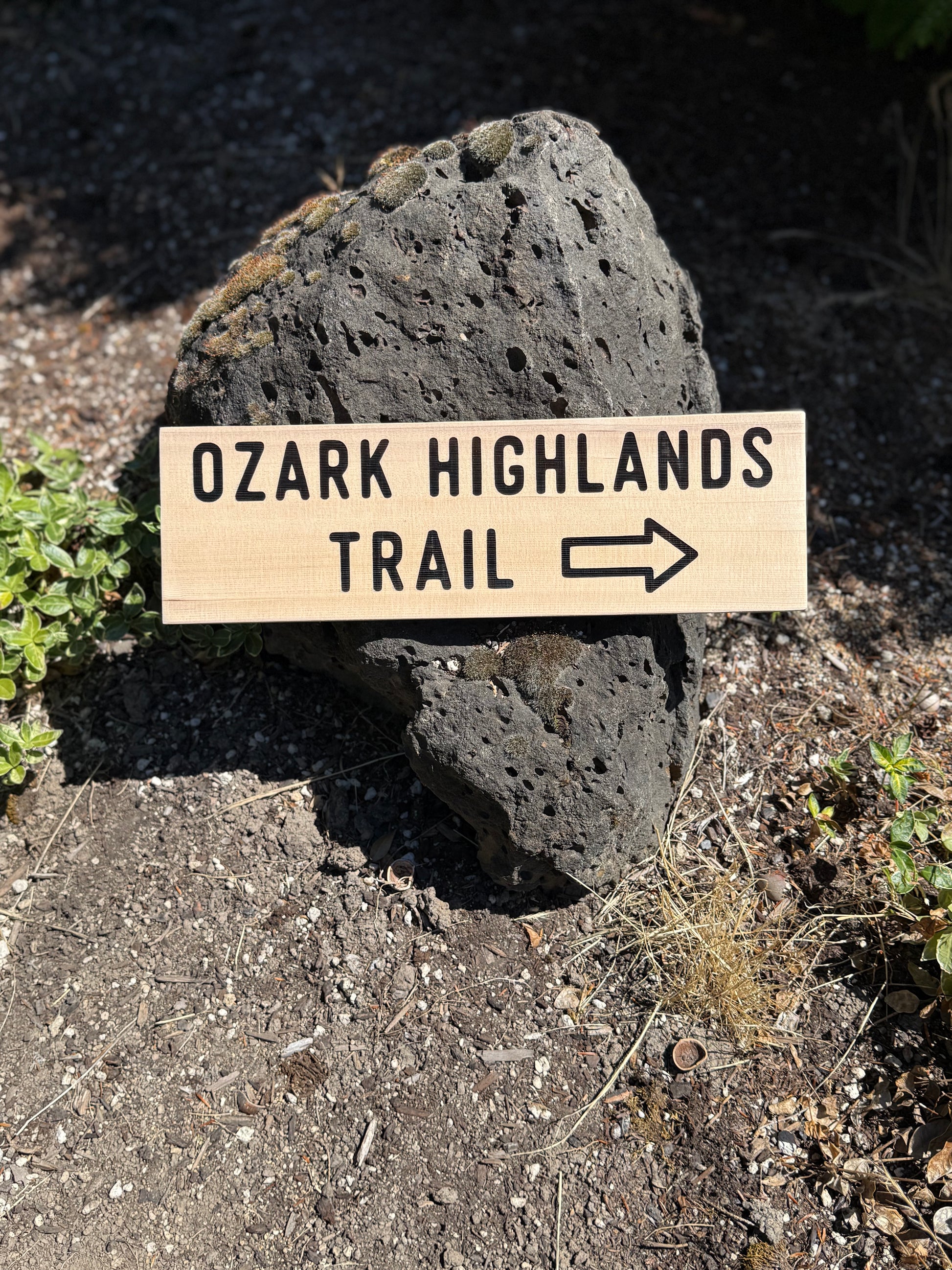 Wooden sign pointing to the Ozark Highlands Trail on a rock in a natural setting.