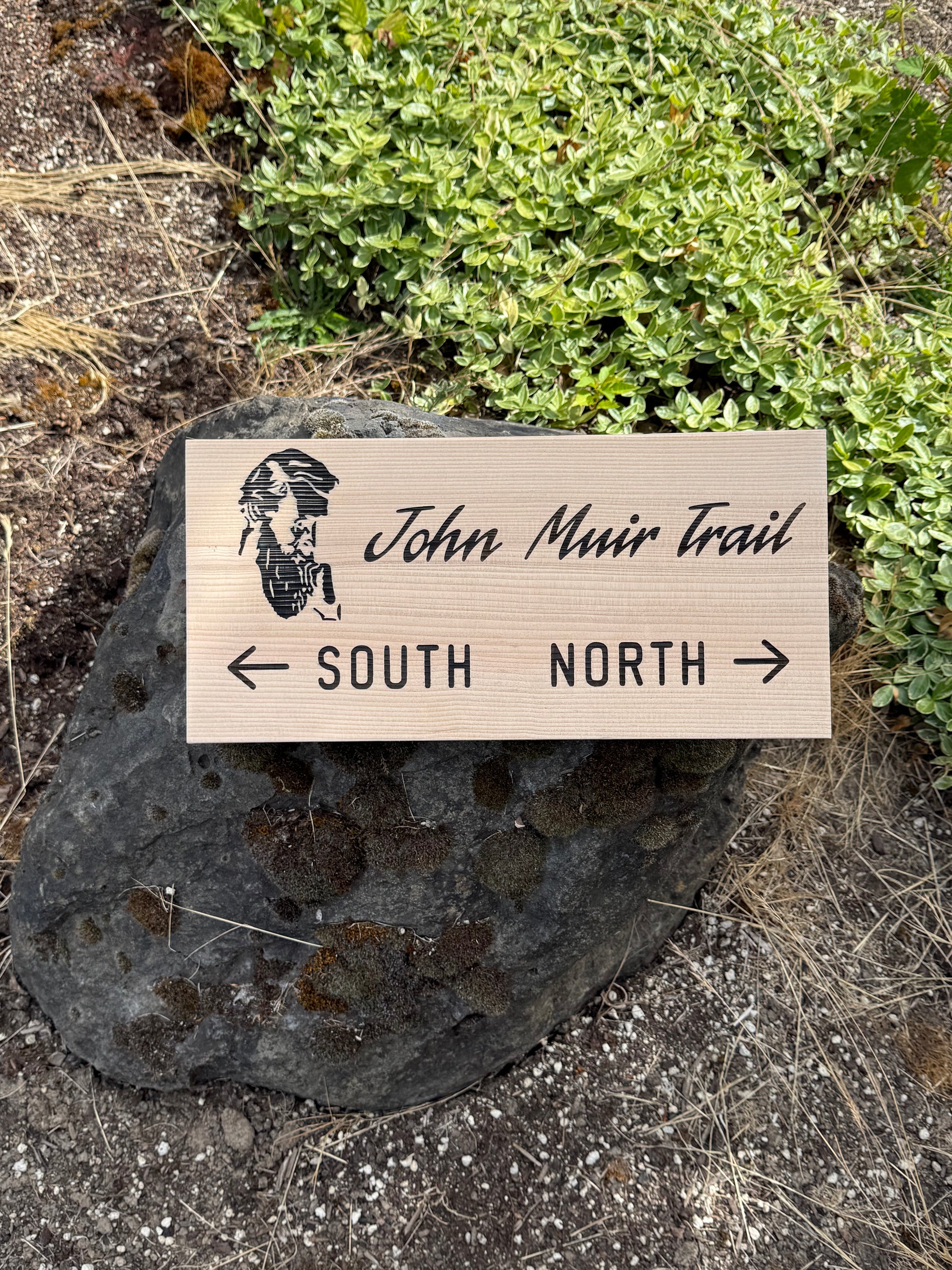 Wooden sign for John Muir Trail with directional arrows on a natural background