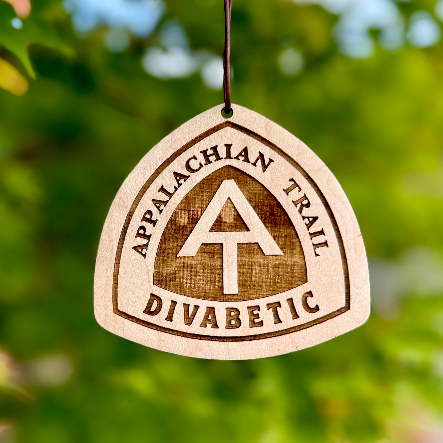 Close-up of an engraved Appalachian Trail wooden tag hanging among green leave