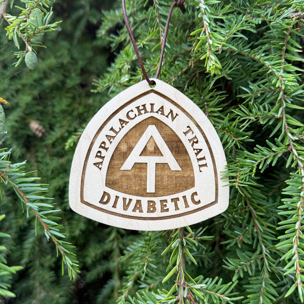 Appalachian Trail wooden hangtag suspended in front of evergreen branches