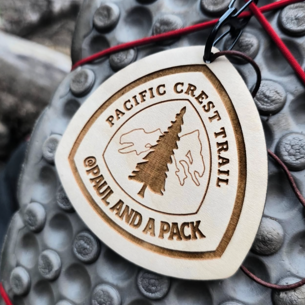 Close-up of a custom engraved wooden trail tag showing its lettering and wood grain