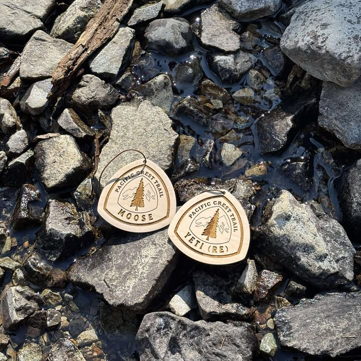 Two wooden hiking tags resting on rocks outdoors